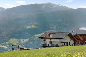 A mountain house with a balcony, a wooden deck, and a view of the surrounding landscape.