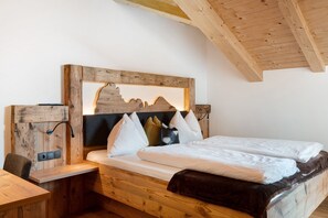 A wooden bed with a mountain design headboard, a bedside table, and a chair.