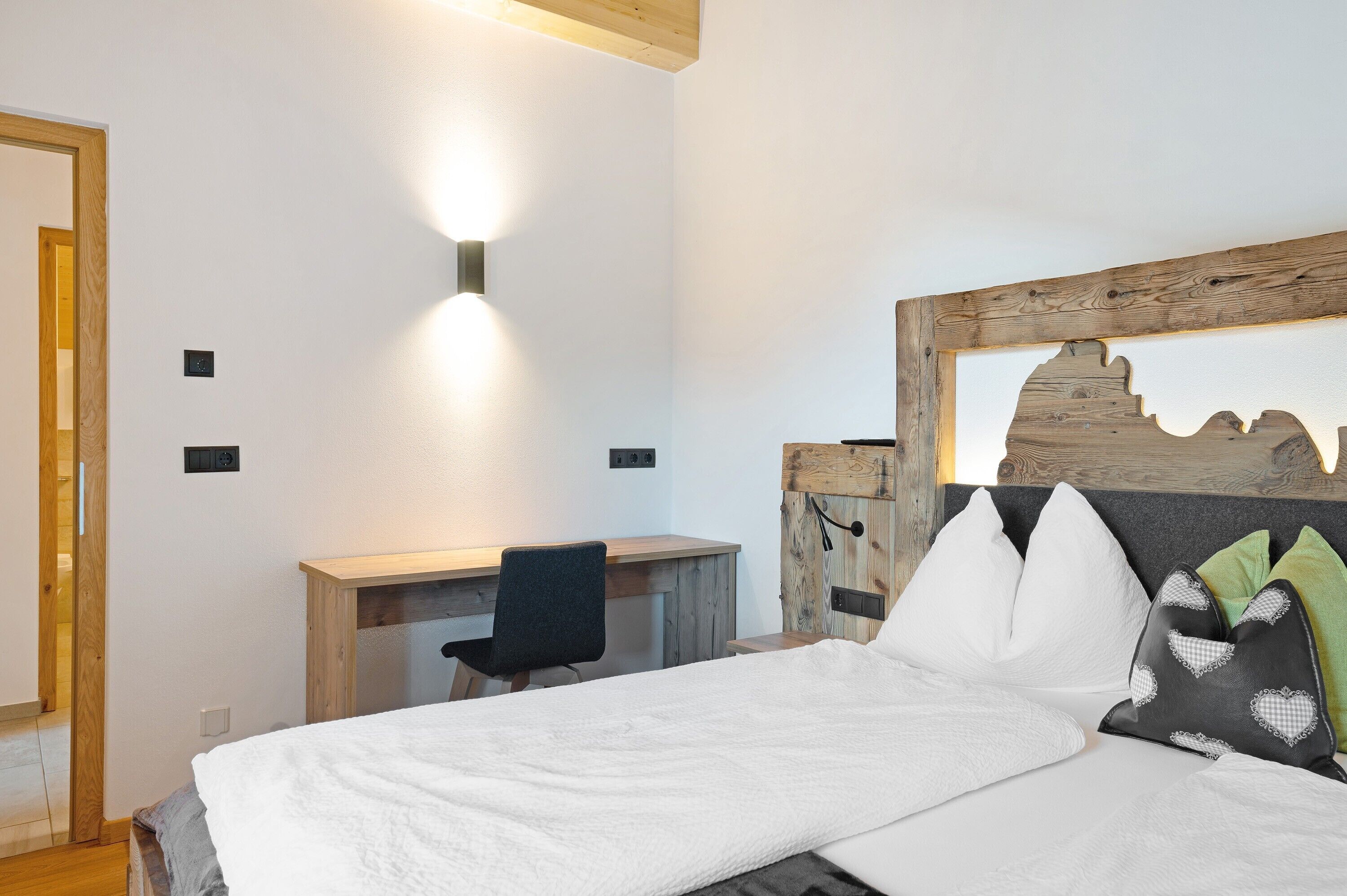 A bedroom with a bed, a desk, and a chair.