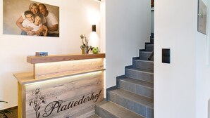 A reception desk with a wooden finish and a sign that reads 'Plattiederhof.' - Holiday Apartment 'Platiederhof Apt Lajen' with Mountain View, Shared Garden & Wi-Fi (Laion)