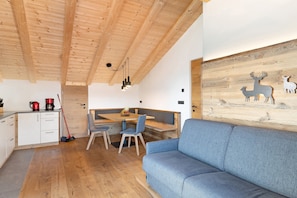 A modern interior with a wooden ceiling, a dining area with a bench, a sofa, and a wall with animal silhouettes.