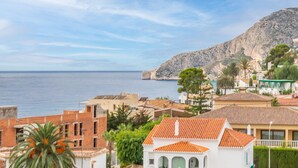 A coastal town with buildings, a mountain, and the sea.