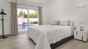 A bedroom with a bed, a nightstand, a lamp, and a view of a swimming pool. - Villa "Bennu - Lujo Y Confort" near Beach with Private Pool & Wi-Fi (Calpe)