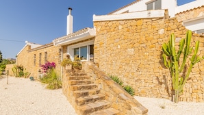 A stone house with a staircase leading to a door, surrounded by cacti and other plants. - Villa "Bennu - Lujo Y Confort" near Beach with Private Pool & Wi-Fi (Calpe)