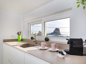 Una cocina moderna con un ventanal grande, un lavamanos y una cafetera.