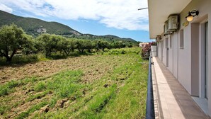 A hotel corridor with a view of a vineyard and hills. - JHoliday Apartment "Tropical 1" with Shared Garden, A/C & Wi-Fi (Zakynthos)
