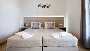 A modern hotel room with a large bed, two bedside tables, a wall-mounted light fixture, and a wooden headboard. - JHoliday Apartment "Tropical 1" with Shared Garden, A/C & Wi-Fi (Zakynthos)