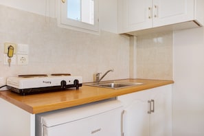 A kitchen with a stove, sink, and white cabinets. - Holiday Apartment "Tropical 4" with Shared Garden, A/C & Wi-Fi (Zakynthos)