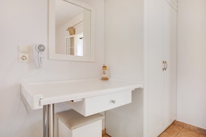 A white bathroom vanity with a mirror, a hairdryer, and a small decorative item on the counter. - Holiday Apartment "Tropical 4" with Shared Garden, A/C & Wi-Fi (Zakynthos)