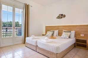A double bed with a wooden headboard, two pillows, a small nightstand, and a view through a glass door. - Holiday Apartment "Tropical 4" with Shared Garden, A/C & Wi-Fi (Zakynthos)