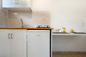 A compact kitchen with white cabinets, a built-in dishwasher, and a small countertop with a stove.