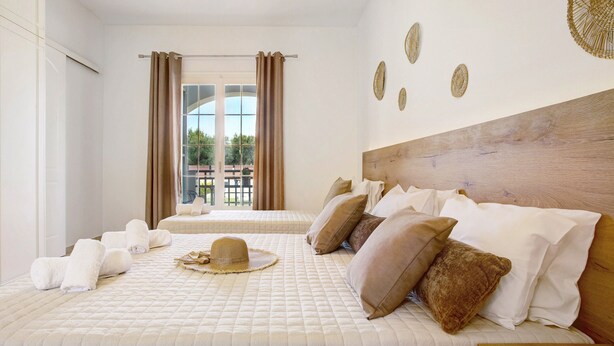 Une chambre d’hôtel avec un grand lit, une tête de lit en bois et une vue sur l’extérieur par une fenêtre.