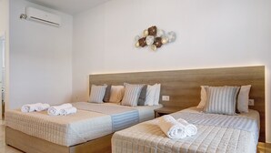 Camera d'albergo con due letti, una testiera in legno e un condizionatore d'aria a parete.