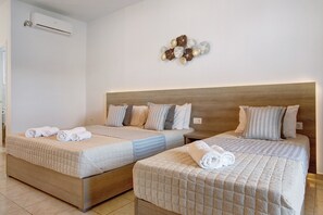 Une chambre d’hôtel avec deux lits, une tête de lit en bois et un climatiseur fixé au mur.
