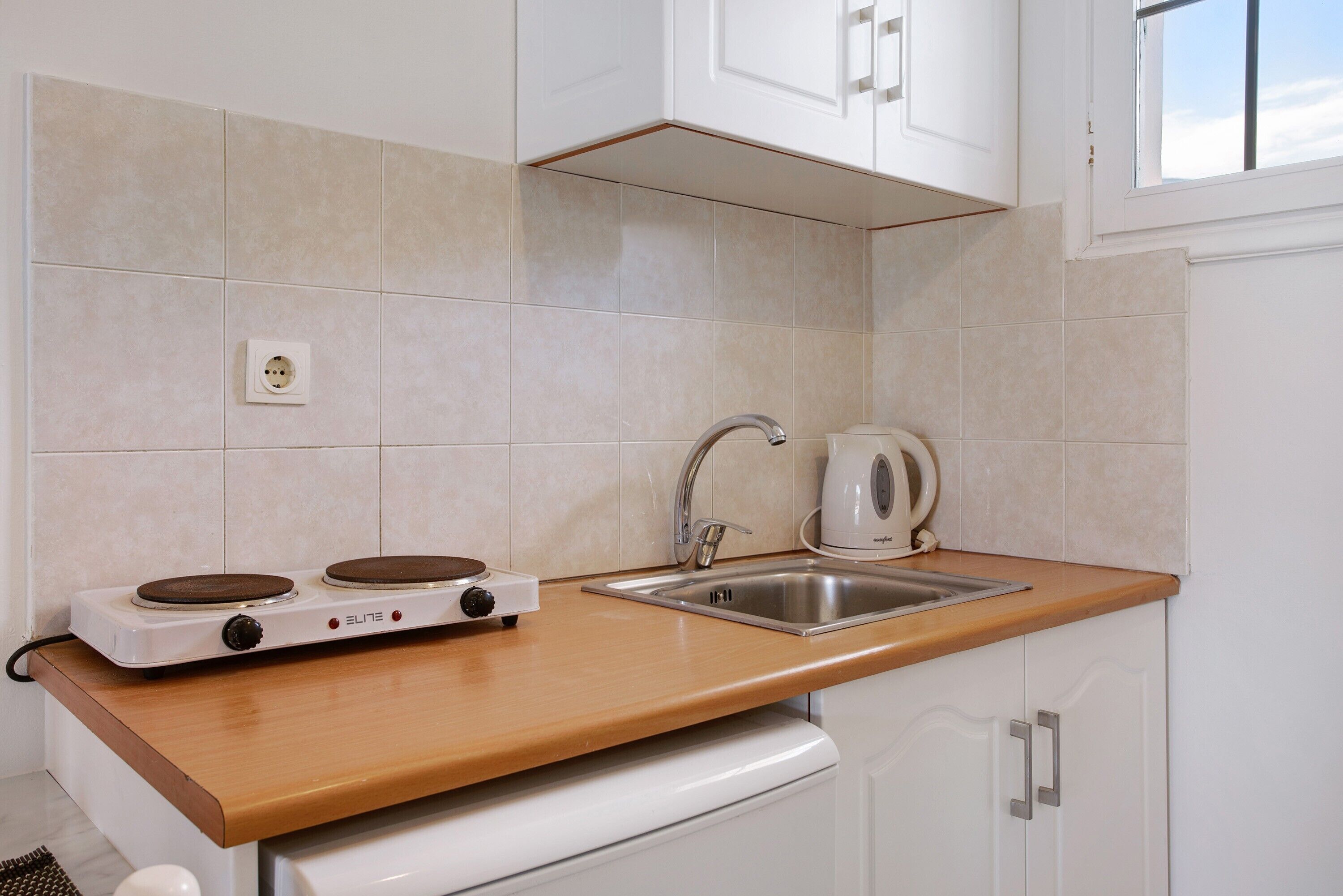 A kitchen with a stove, sink, and cabinets.