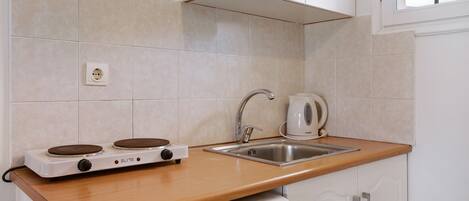 A kitchen with a stove, sink, and cabinets.