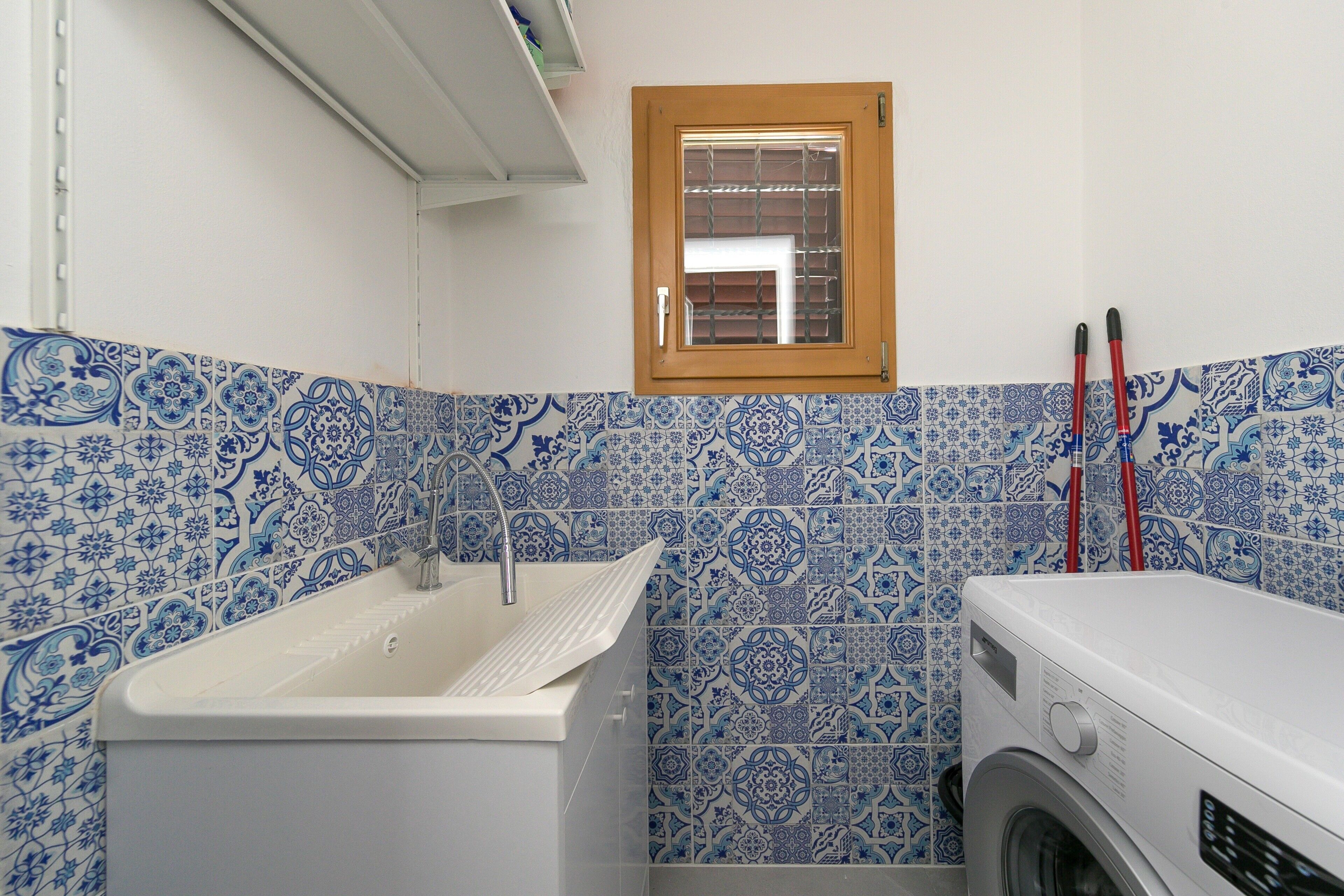 Ein Badezimmer mit Waschbecken, Fenster und Waschmaschine.