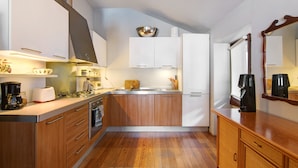 A compact kitchen with wooden cabinets, a built-in oven, a coffee maker, and a sink. - Holiday Home "Bernhouse" with Lake View, Balcony and Wi-Fi (Dorio)