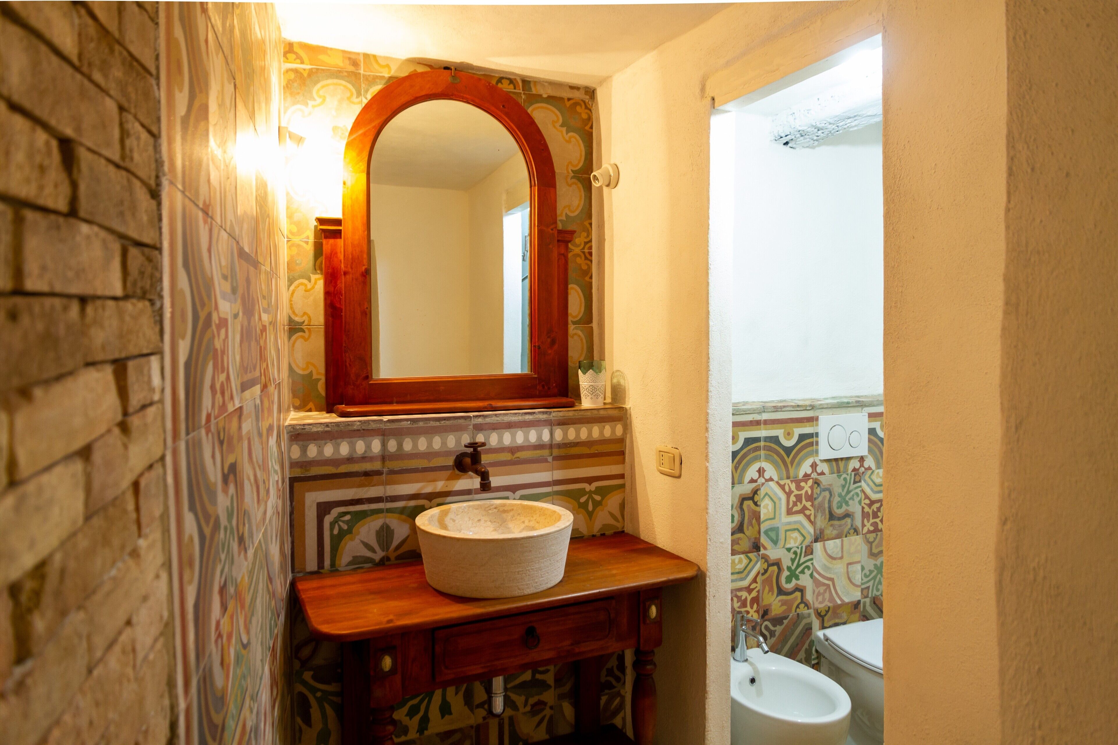 A bathroom with a stone sink, wooden vanity, and a mirror.