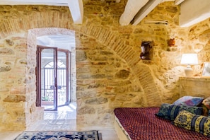 Une pièce aux murs de pierre, avec un lit, une petite table et une fenêtre.