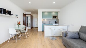A modern kitchen with a microwave, sink, and bar area. There is a dining table with chairs and a sofa in the living area.