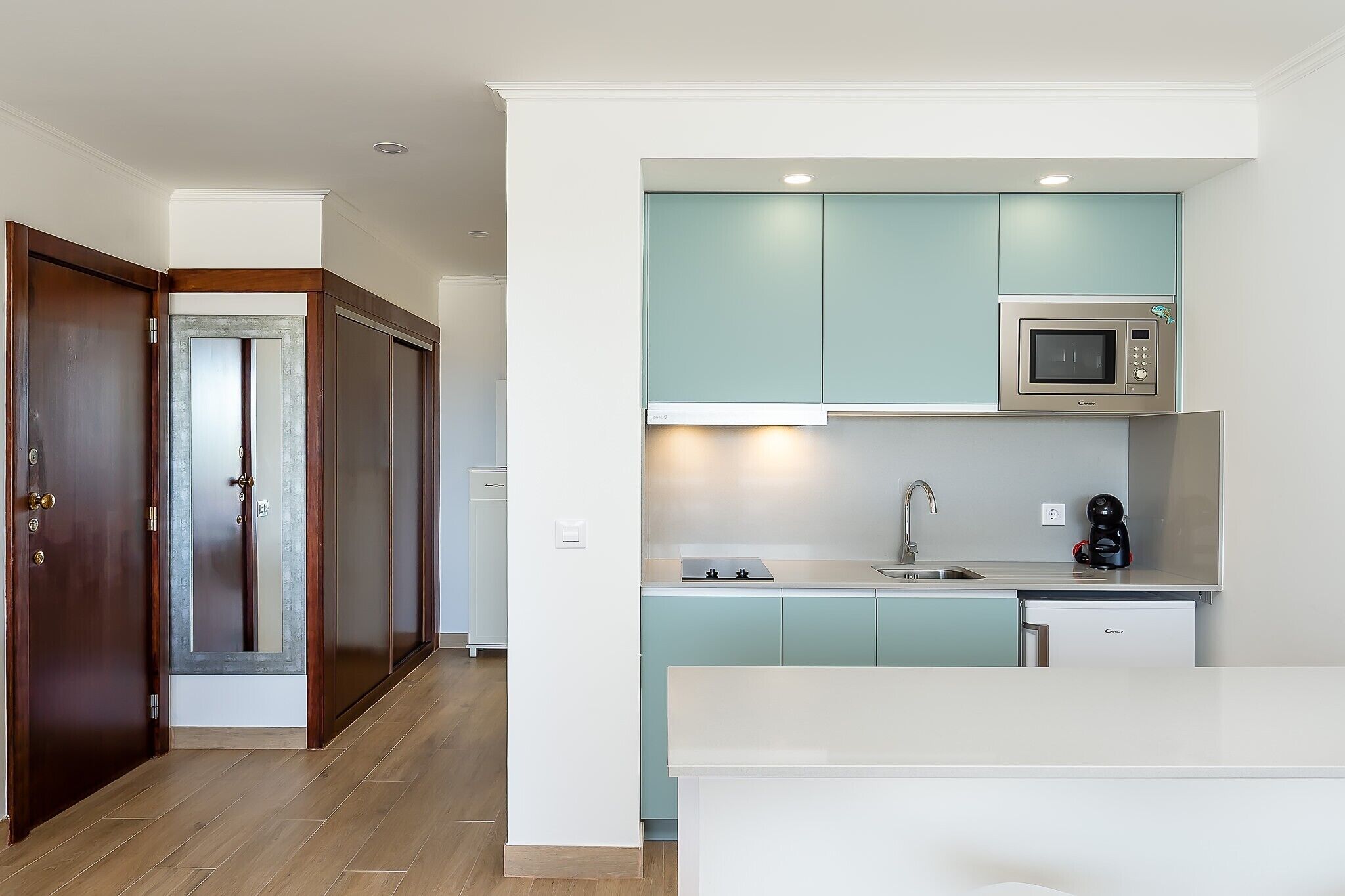 Una cucina moderna con mobili color petrolio, un forno a microonde in acciaio inox e una lavastoviglie integrata.