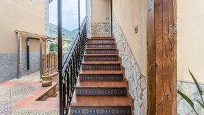 Una escala amb rajoles dibuixades, una porta de fusta i vista a un turó.