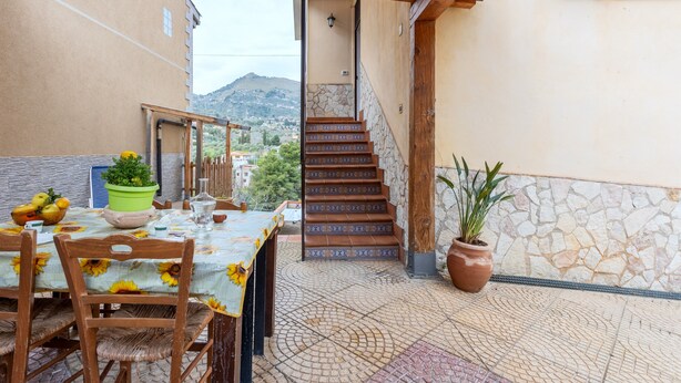Un pati amb taula preparada per dinar, una escala i plantes en testos.