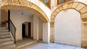 Un patio con una escalera de piedra, arcos y suelo de baldosas.