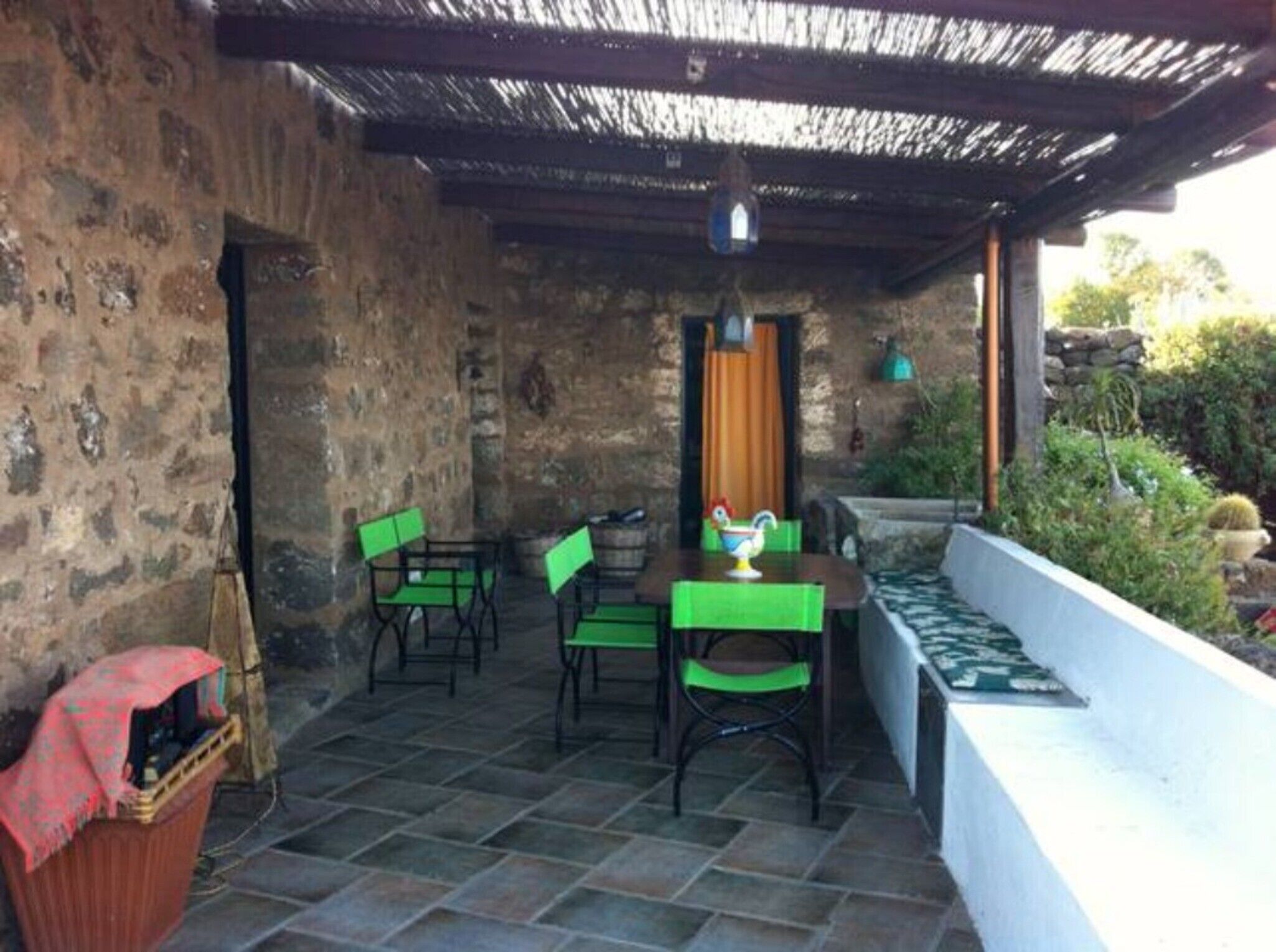 Eine Terrasse mit Steinmauern, einem Tisch mit Stühlen und einem kleinen Gartenbereich.
