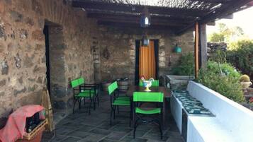 Eine Terrasse mit Steinmauern, einem Tisch mit Stühlen und einem kleinen Gartenbereich.