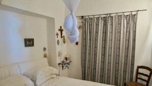 Ein Schlafzimmer mit Bett, Stuhl, Vorhang und Wanddekorationen.