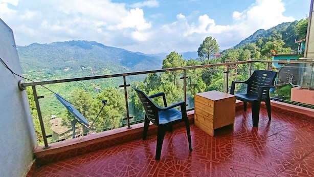 Un balcon doté d’un sol à motifs rouges, de deux chaises noires et d’une table en bois.