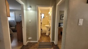 A hallway leading to a bathroom with a sink and a shower. - Main Floor Suite (Stettler)