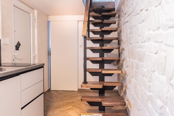 Una escalera de madera con barandillas negras que conduce a una puerta.