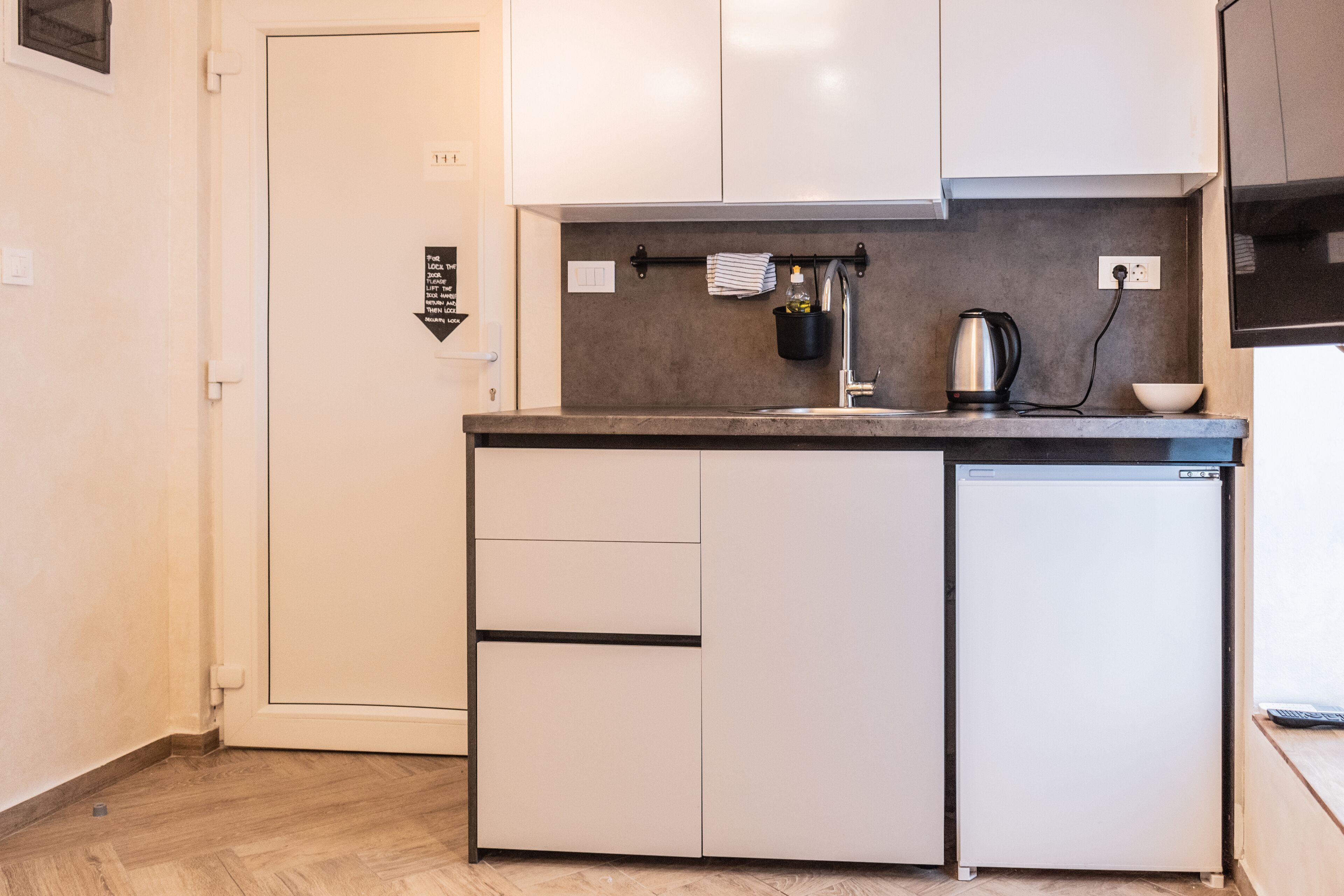 A compact kitchen with white cabinets, a built-in dishwasher, a coffee maker, and a small countertop.