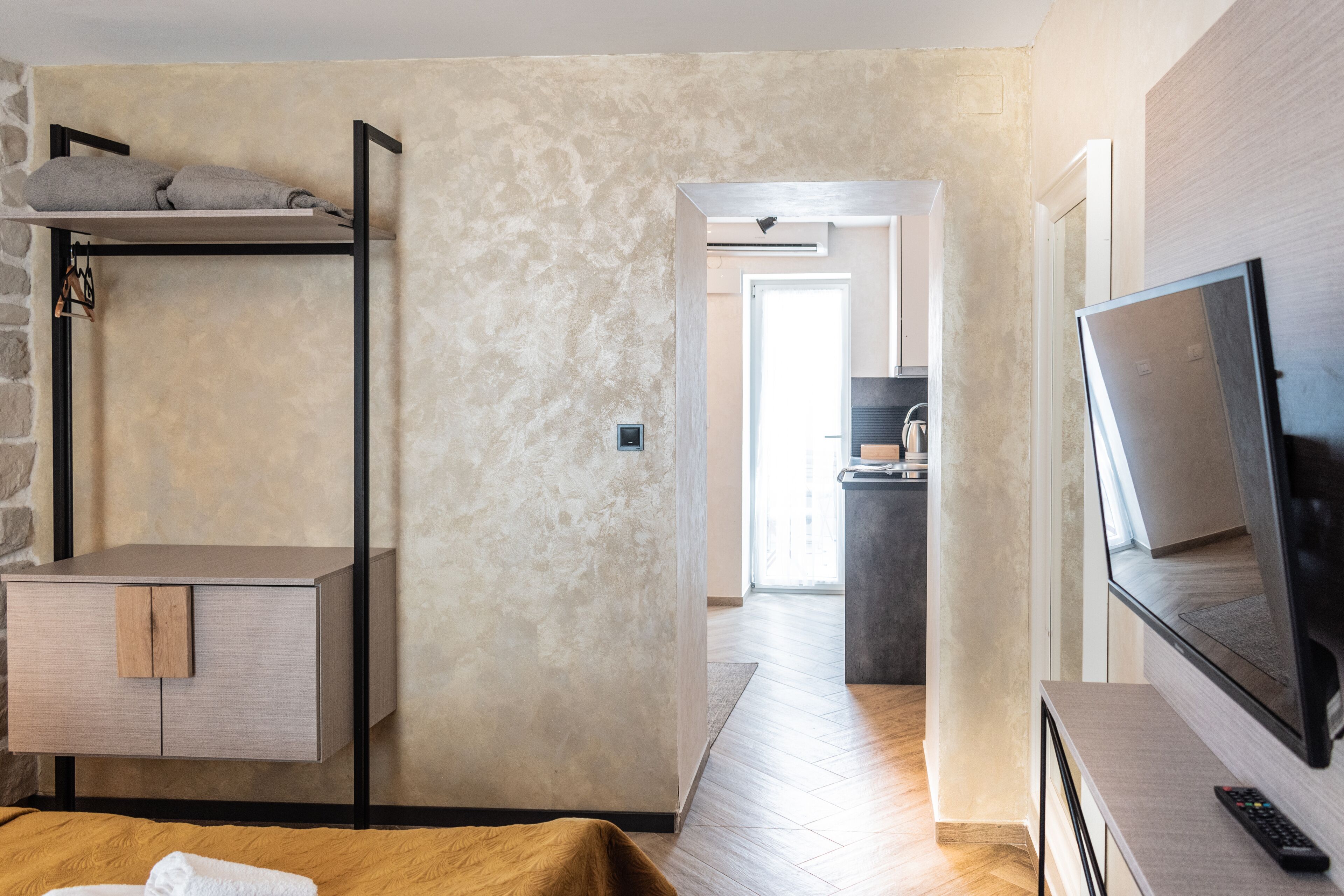 Une chambre moderne avec un lit superposé, une télévision et un coin cuisine à l’arrière-plan.