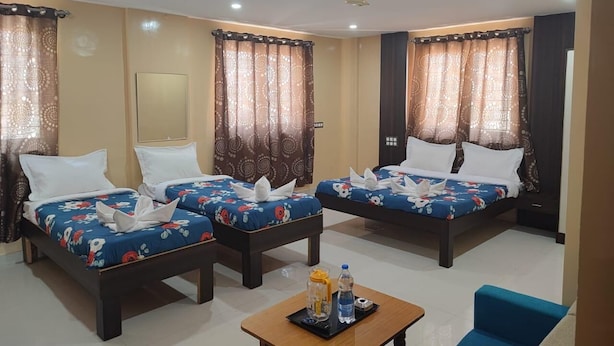 A hotel room with two beds, a ceiling fan, and a small table with toiletries. - Hotel Habitat Comforts (Bengaluru)