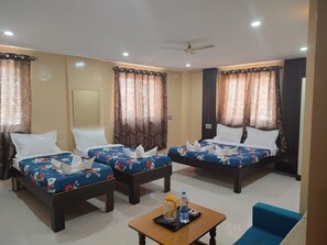 Habitación de hotel con dos camas, un ventilador de techo y una mesita con artículos de aseo.