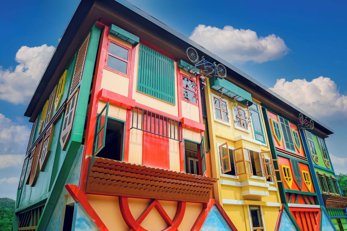A colorful building with multiple windows and a bicycle mounted on the roof.
