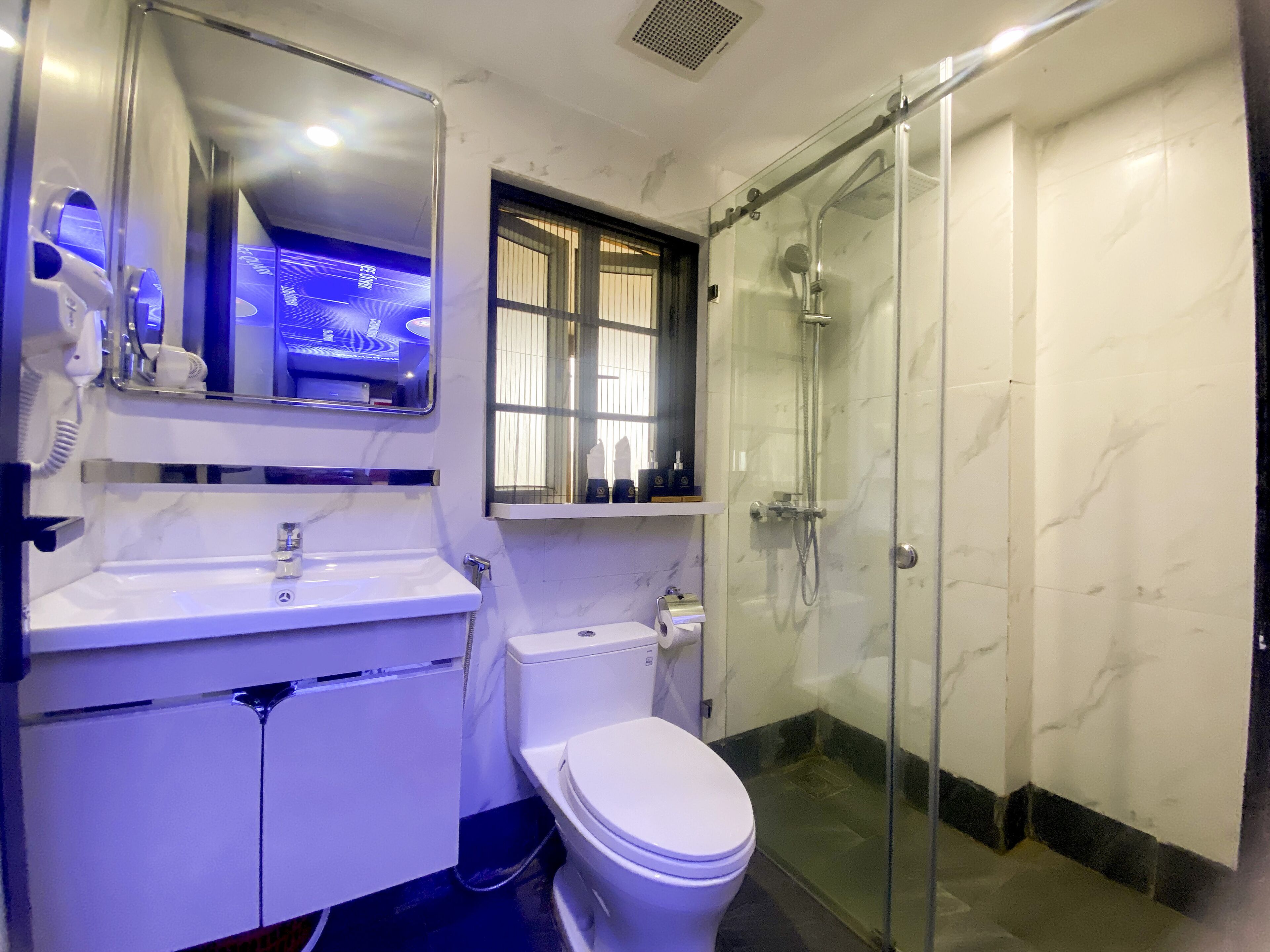 Een moderne badkamer met een douchecabine van glas, een witte wastafel en een toilet.