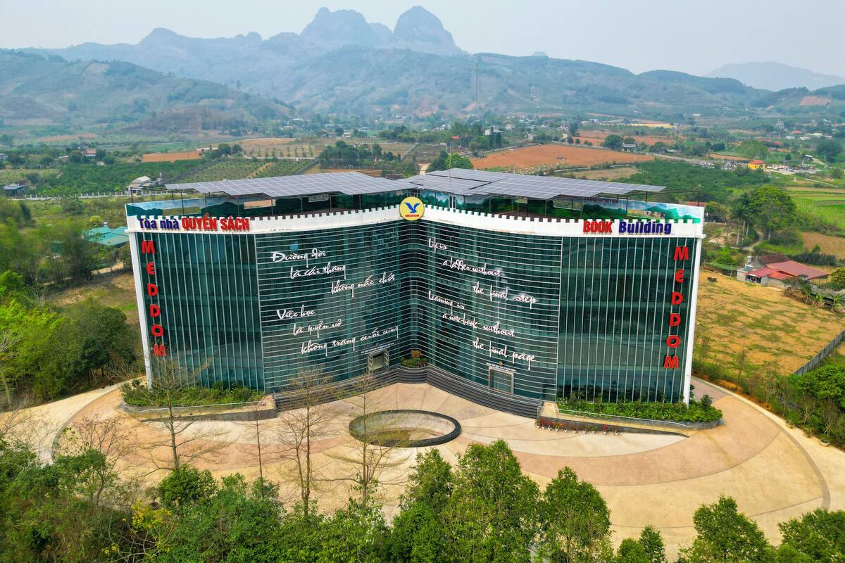 A modern building with a curved glass facade and a rooftop garden.