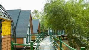 A pathway leading to a row of wooden cabins with a green railing. - MEDDOM Park (Thung Nai)