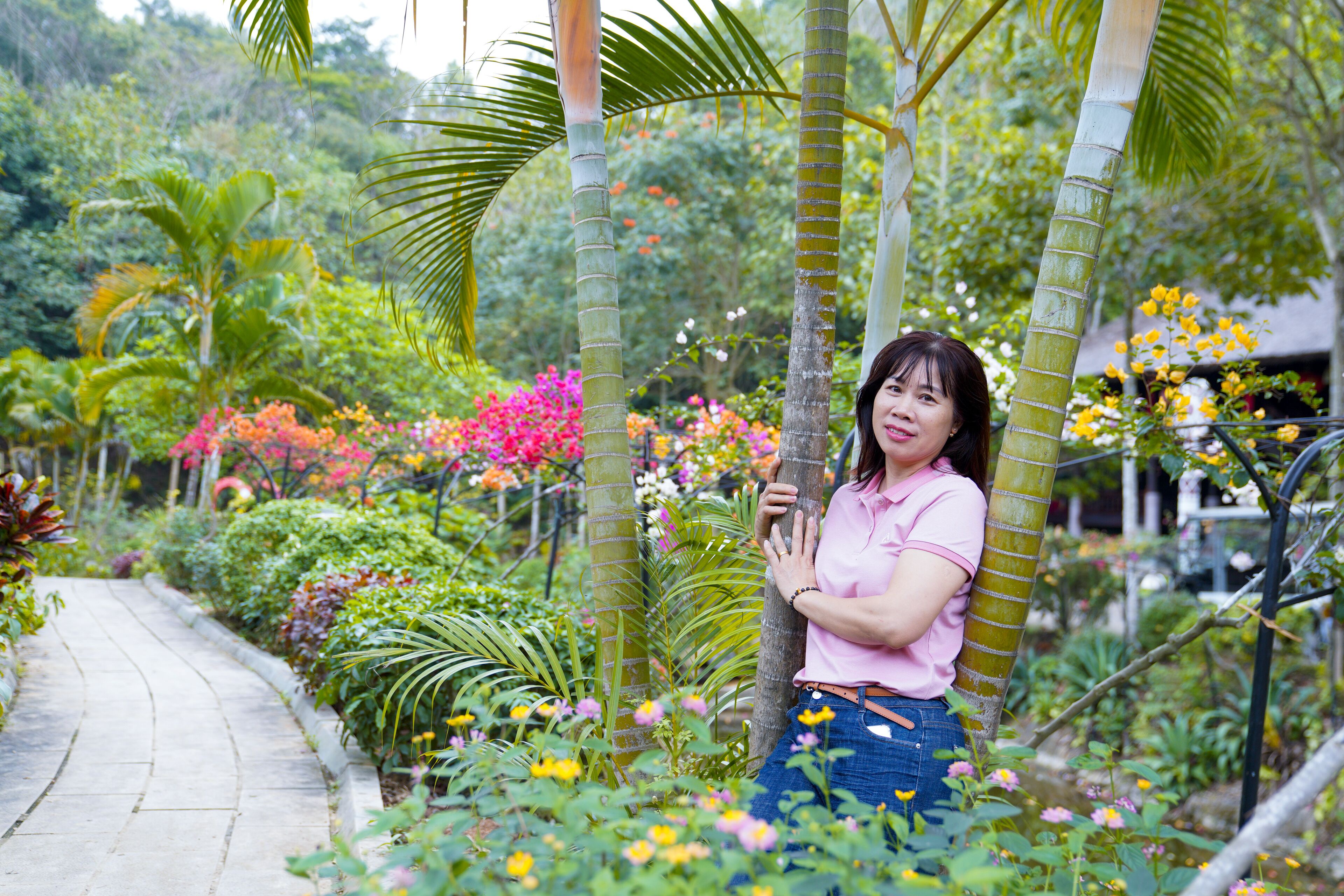 Une femme se tient dans un jardin, entourée de différentes plantes et de fleurs.