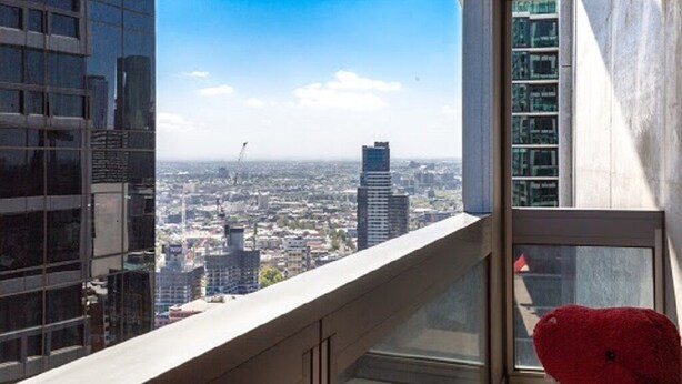 Um edifício alto com vista para o horizonte urbano através de uma janela.