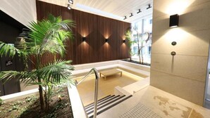 Uma área interna de piscina moderna com parede de madeira, um banco e uma palmeira.