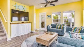 A living room with a TV, sofa, coffee table, and a ceiling fan. - Good Times & Tan Lines on Perdido Key! (Pensacola)