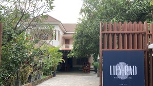 A paved pathway leading to a villa with a signboard for LILY PAD Boutique Hotel.
