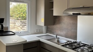 A modern kitchen with a gas stove, stainless steel sink, and a window with a view of greenery. - Mobilhome Gorges de Verdon (Provence-Alpes-Côte d'Azur)