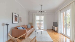 A modern living room with a sofa, a coffee table, and a TV. - Homey 2BR Apartment in Cholargos (Cholargos)